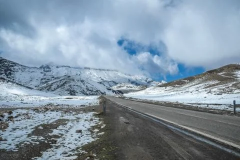 A road surrounded by snow capped mountains in the High Atlas range. Morocco. Stock Photos