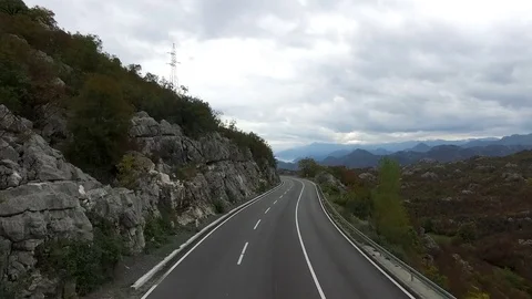 Road through the grassy hills. Footage.Mountain road. Cloudy summer day. Travel Stock Footage