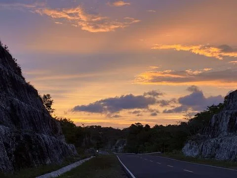 Road through rocky cliffs at sunset sky Stock Photos