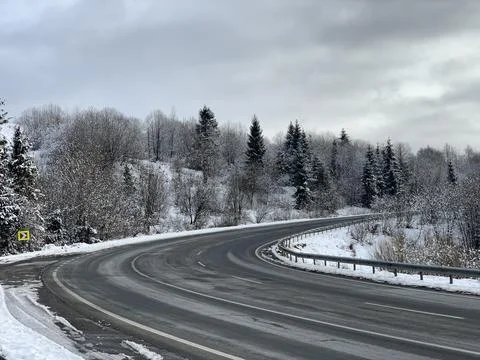 The road through the winter forest. A path in the mountains along a snowy roa Stock Photos