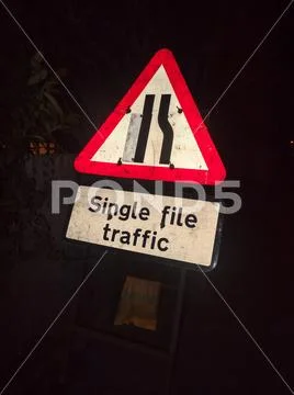 Road traffic sign at night construction work single file traffic Stock Photos