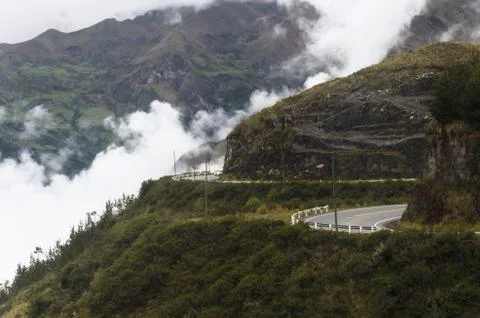 Road with trees and mountains with cloudy sky background. Stock Photos