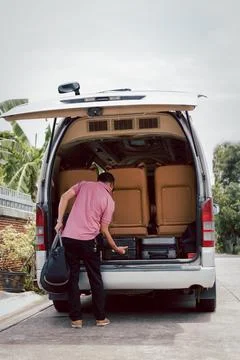 Road trip driver loading luggage on traveling van. Stock Photos