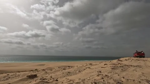 Off-road vehicle driving on sandy dune with ocean under cloudy sky, boa vista Stock Footage 302584591