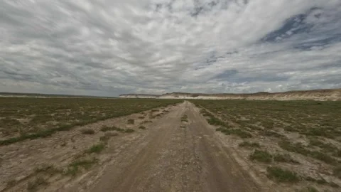 Off-road vehicle navigating dirt path through expansive grassland landscape Stock Footage 342502572