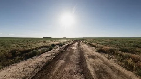 Off-road vehicle navigating dirt path under bright sun in open landscape Stock Footage 342502823