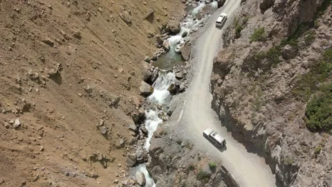 Off road vehicle navigating rocky gorge alongside flowing glacial rapid Stock Footage 345622200