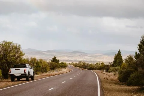 Off-road vehicle next to empty road in Australian outback Stock Photos