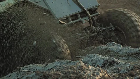 An off-road vehicle splashes through thick mud. Its spinning tire creates Stock Footage 344876747