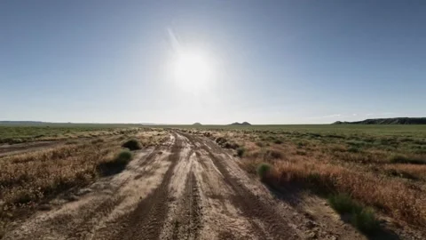 Off-road vehicle traverses dirt path under bright sun in open landscape Stock Footage 341791526