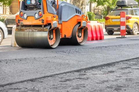 A road vibratory roller compacts fresh asphalt on the carriageway. Stock-Fotos