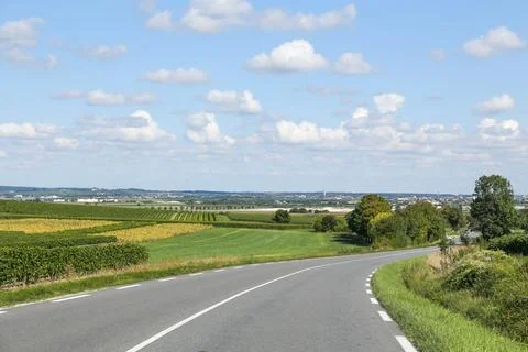 A road with a white line down the middle and a blue sky above Stock Photos