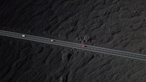The road with white lines is surrounded by black volcanic lava. Sticking rocks.  Stock Footage 102738677