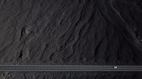 The road with white lines is surrounded by black volcanic lava. Sticking rocks.  Stock Footage 102741136