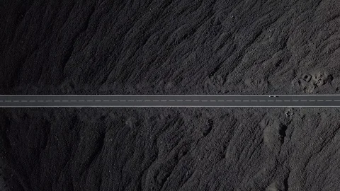 The road with white lines is surrounded by black volcanic lava. Sticking rocks.  Stock Footage 102742539