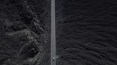The road with white lines is surrounded by black volcanic lava. Sticking rocks.  Stock Footage 102742927