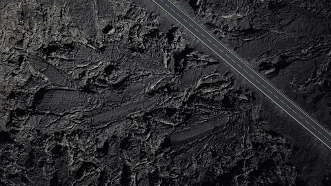 The road with white lines is surrounded by black volcanic lava. Sticking rocks.  Stock Footage 102743100