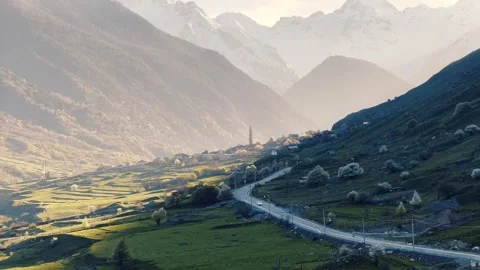 A road winding through a mountain valley with a backdrop of towering mountains Vídeo Stock 268337312