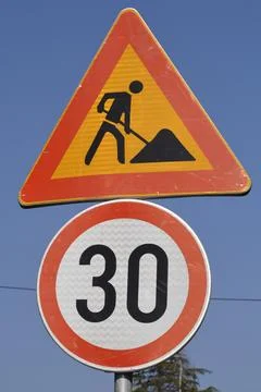 Road work and speed limit traffic signs against blue sky Stock Photos