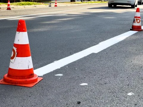 Road work area is outlined by traffic cones and freshly painted white lines.. Stock Photos