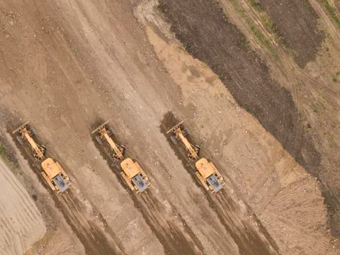 Road work. Large machine work on a new road construction site. Aerial view fr Stock Photos
