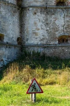 Road work warning sign before ancient stone wall of Medzhybizh fortress Photos