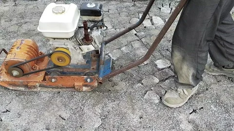 Road worker compacting a cobblestone sidewalk with  compactor machine Vídeos de archivo 329615739