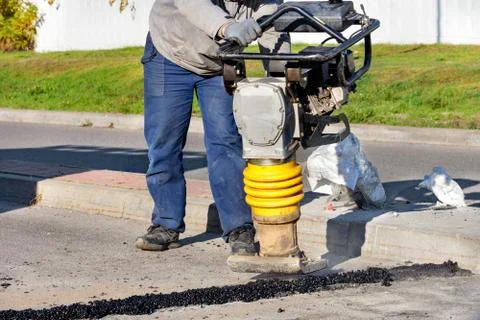 The road worker holds a bouncing vibratory rammer when repairing the roadway. Foto stock