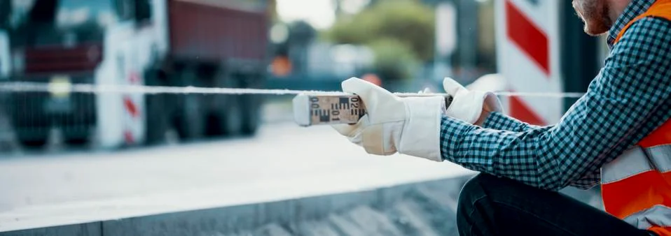 Road worker leveling a string line, holding the tool with safety gloves and a Stock Photos