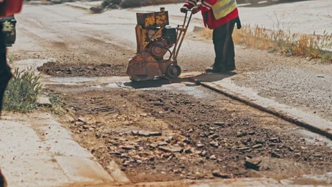 Road worker operating floor saw and cutting asphalt on street. Road works Stock Footage 242167707