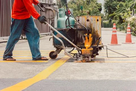 Road worker paint traffic lines on asphalt road surface. Stock Photos