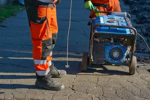 A road worker prepares to start a generator with a starter actuator cord. Stock Photos