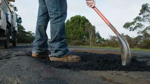 Road worker repairing a pothole on a busy highway. Stock Footage 93103653