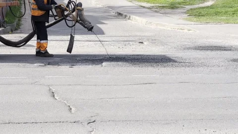 Road worker repairs damaged asphalt surface of road using specialized equipment, Video stock 342230747