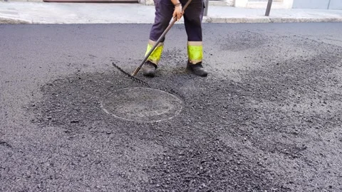 Road worker treating warm mix asphalt during road maintenance Stock Footage 253231219