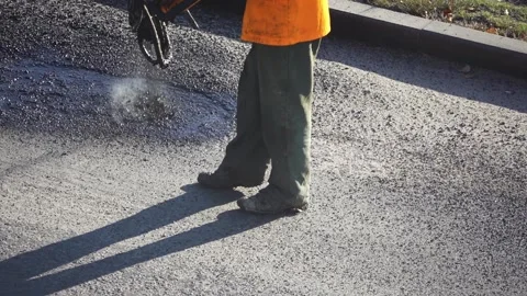 Road worker using specialized equipment embeds small pits on the asphalting o Stock Footage 134208929
