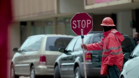 Road worker yawning while holding a stop sign 스톡 동영상 79851430