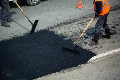 Road workers are paving. Section of road and wooden tools in hands. Stock Photos