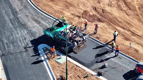 Road workers cleaning up road edges after paving machine has done its work Stock Footage 279354951