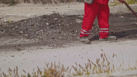 Road workers manually shoveling crushed asphalt. Patches on broken roads Video stock 242177988