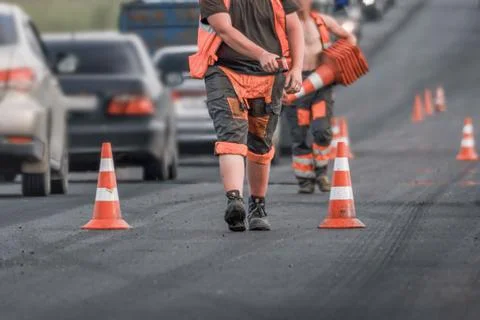 Road workers placing traffic cones during road repair on a busy city street.. Stock Photos