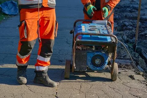 Road workers prepare to start a generator with a starter actuator cord Stock Photos
