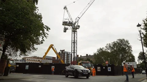 Road workers wave traffic around a construction site, residential London Stock Footage 97242787