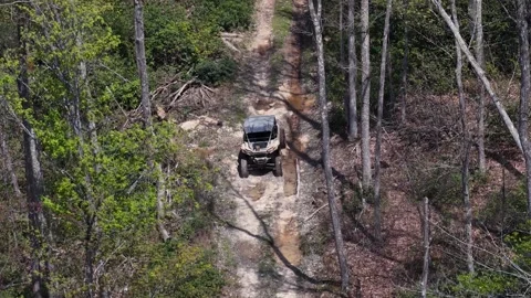 Off-roading vehicle driving down dirt path away from drone Stock Footage 344999294