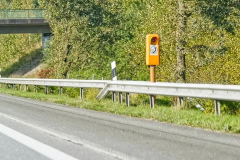 A roadside view featuring a speed camera mounted on an orange pole, with a .. Stock Photos
