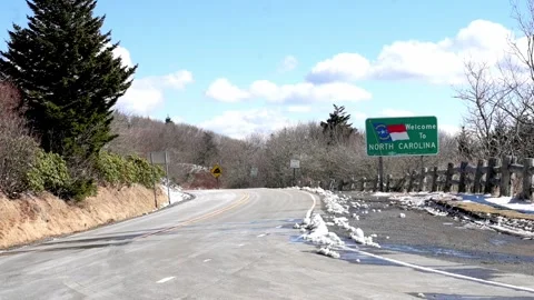 Roadside view featuring a Welcome to North Carolina sign amidst a winter Vídeo Stock 280370372