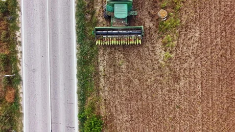 Roadside view of a tractor working in a field beside a moving vehicle on a rural Stock Footage 345454621