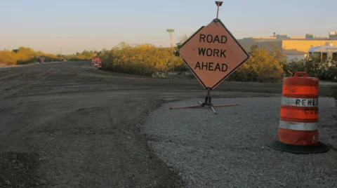 Roadwork Ahead Sign sits on Fresh Asphalt by a Traffic Barrel Stock Footage 64363903