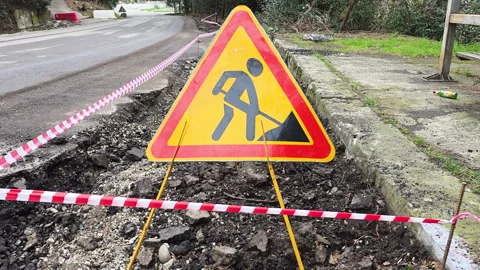 Roadwork warning sign on roadside marking fresh trench and redwhite tape 動画素材 330259989