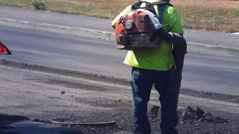 RoadworkerAirBlowingAsphalt Stock Footage 105880917